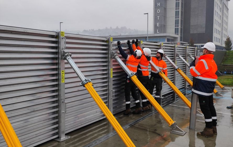 Workers insert the last few modular steel boards to complete the temporary flood gate.